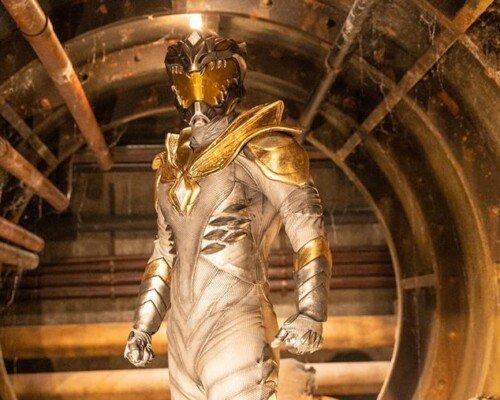 A heroic figure stands in a glowing white suit