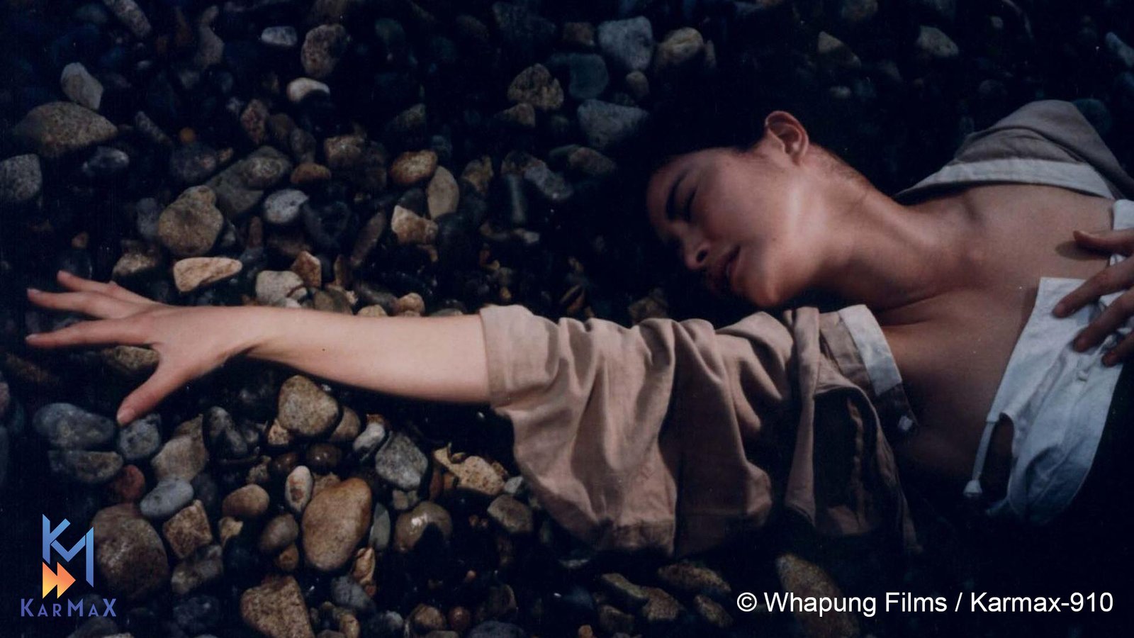 A woman lays on the ground reaching for something as seen in a classic film.