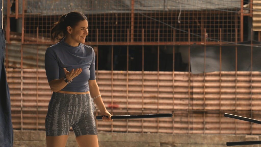 A woman holds a stick as a practice weapon.