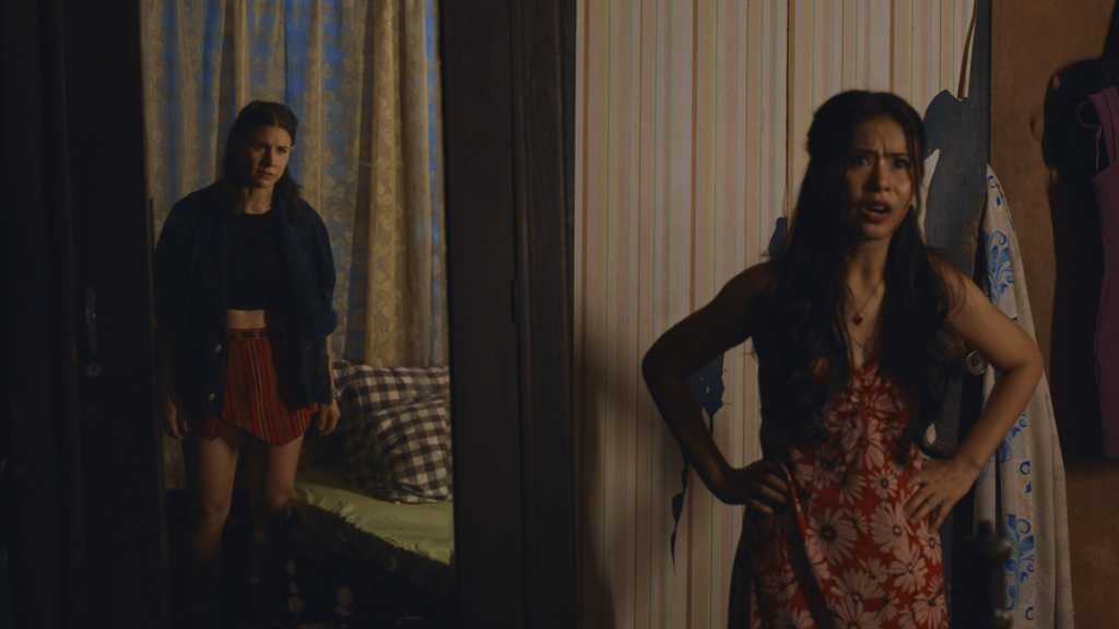 Two women standing in a dark-lit room.